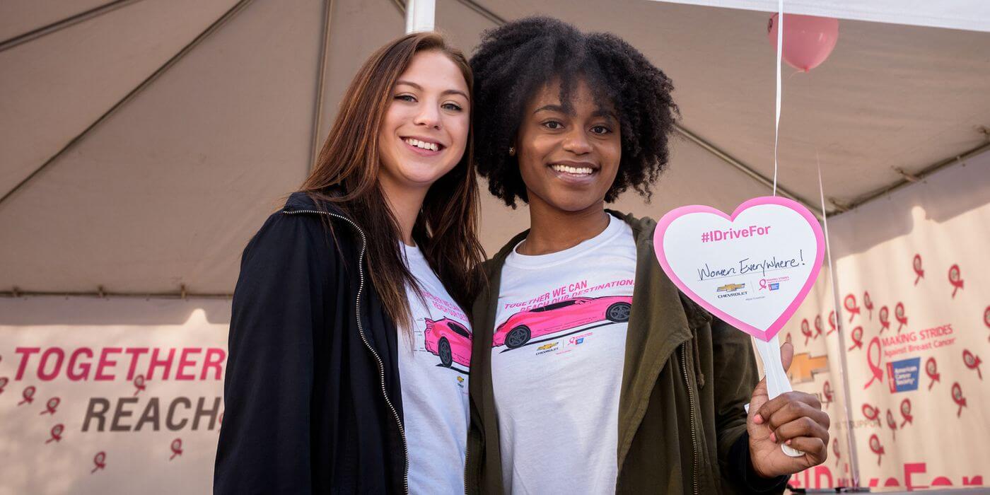 image of 2 women posing and one holding up a sign